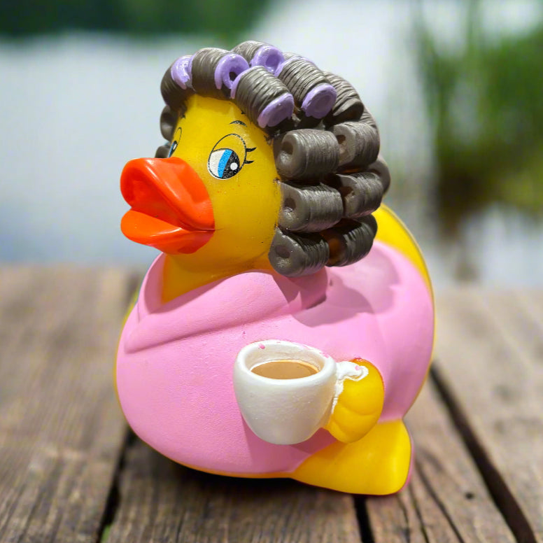 Colorful rubber duck with a pink top and yellow body on a textured surface.