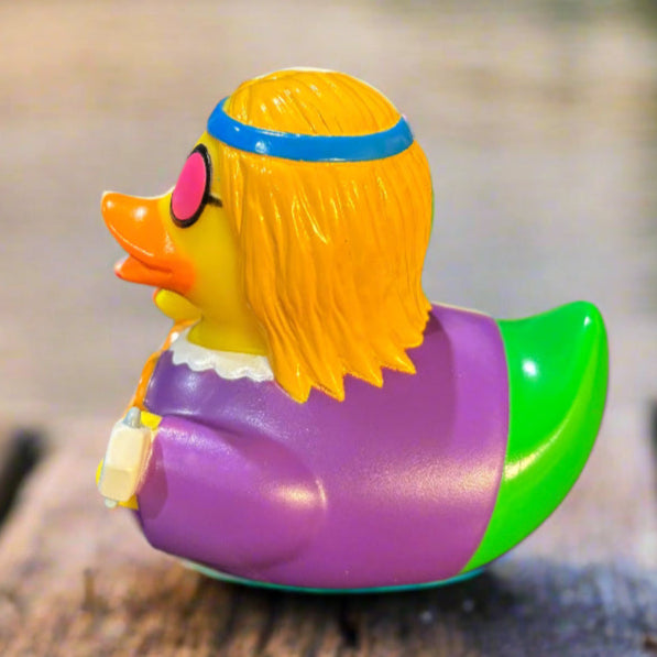 Colorful rubber duck with yellow hair, pink sunglasses, and purple outfit on a wooden surface.