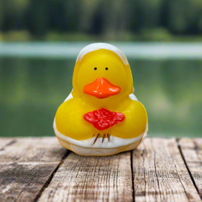 Yellow rubber duck with a red bow tie on a wooden surface