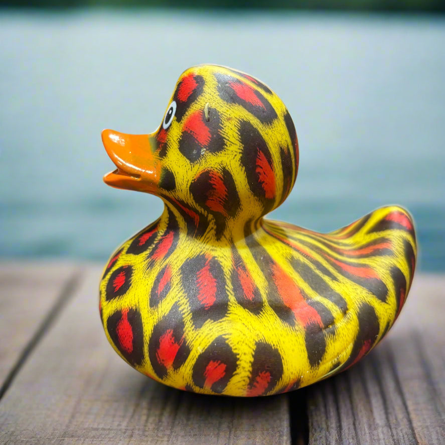 Colorful duck-shaped object with black, red, and yellow pattern on a dark surface.