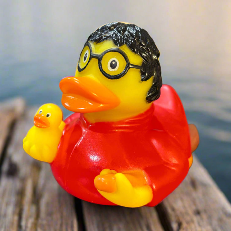 Rubber duck with a red shirt and yellow accents on a dark surface