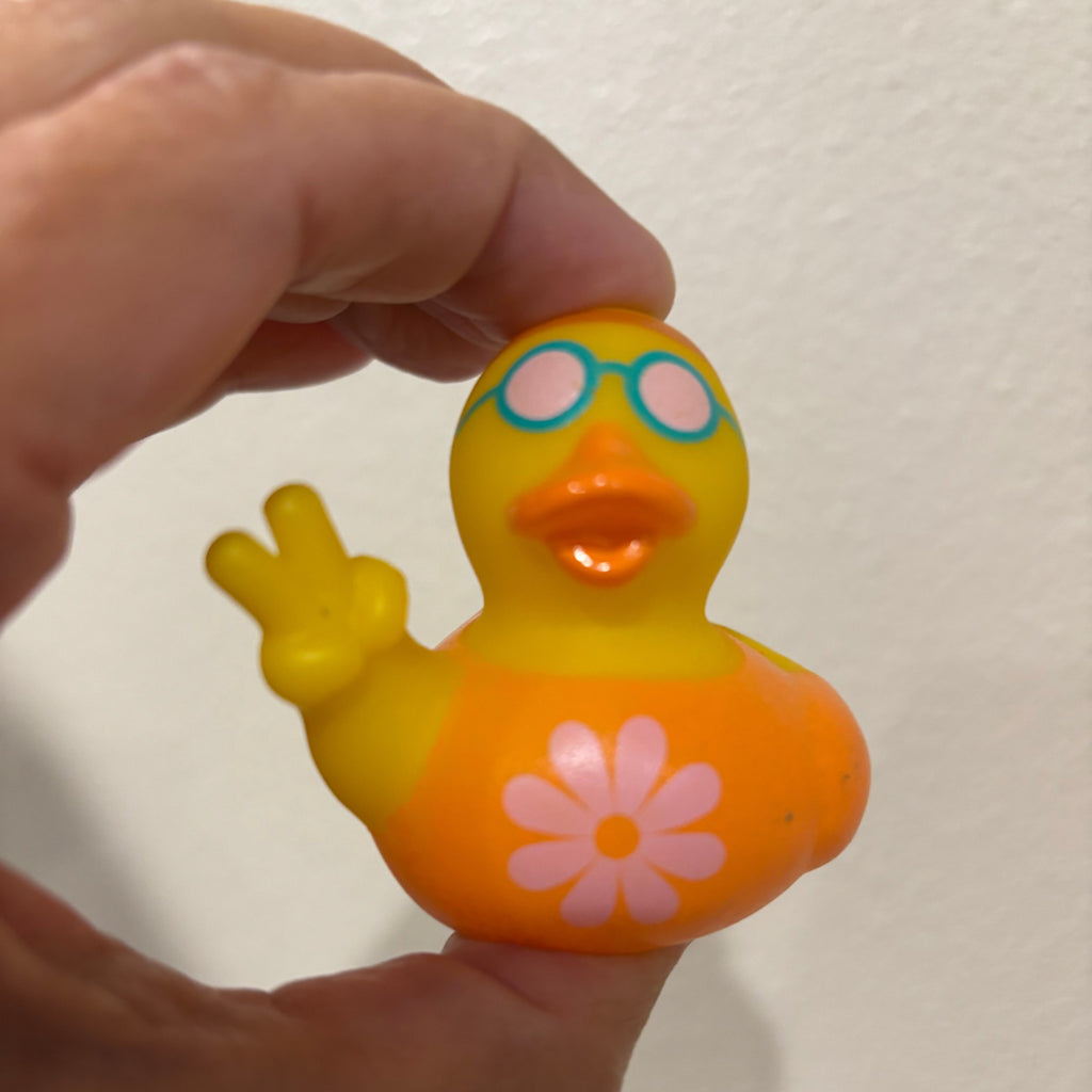 Colorful duck-shaped toy held by a hand against a plain background