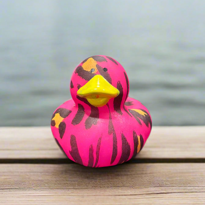 Pink and yellow rubber duck on a black surface with a blurred background