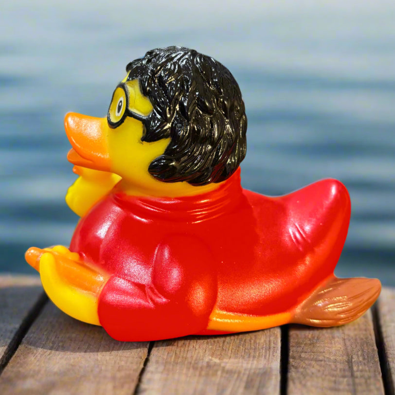 Rubber duck with red cape and black hair on a dark surface