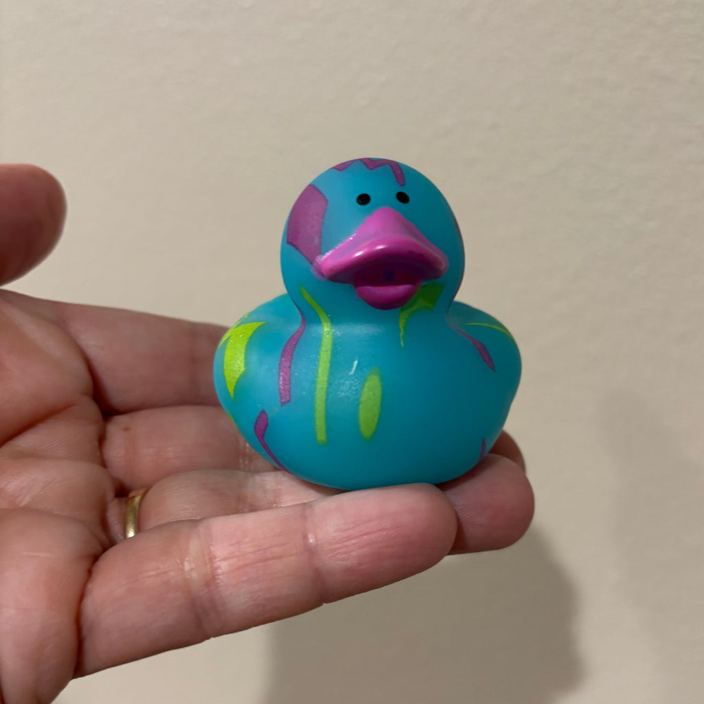 Hand holding a colorful rubber duck against a plain background