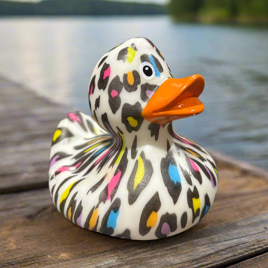 Colorful rubber duck on a dark surface with a blurred background of bottles.