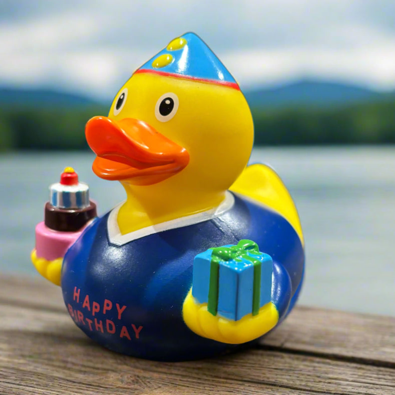Colorful rubber duck with a blue hat and 'Happy Birthday' message on a dark surface.