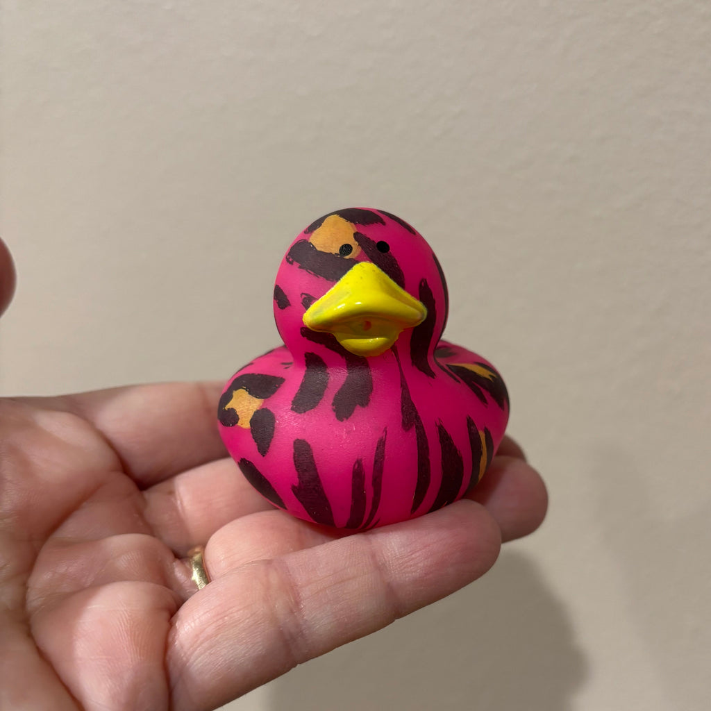 Hand holding a pink and black patterned object against a plain background