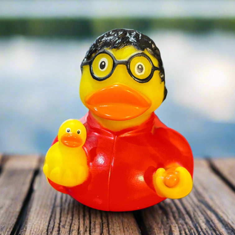 Small red and yellow rubber duck with glasses on a dark surface