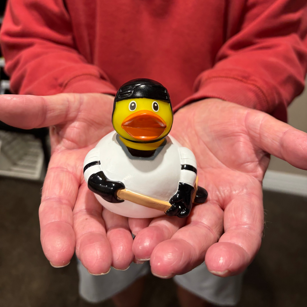 Person holding a small rubber duck dressed as a hockey player