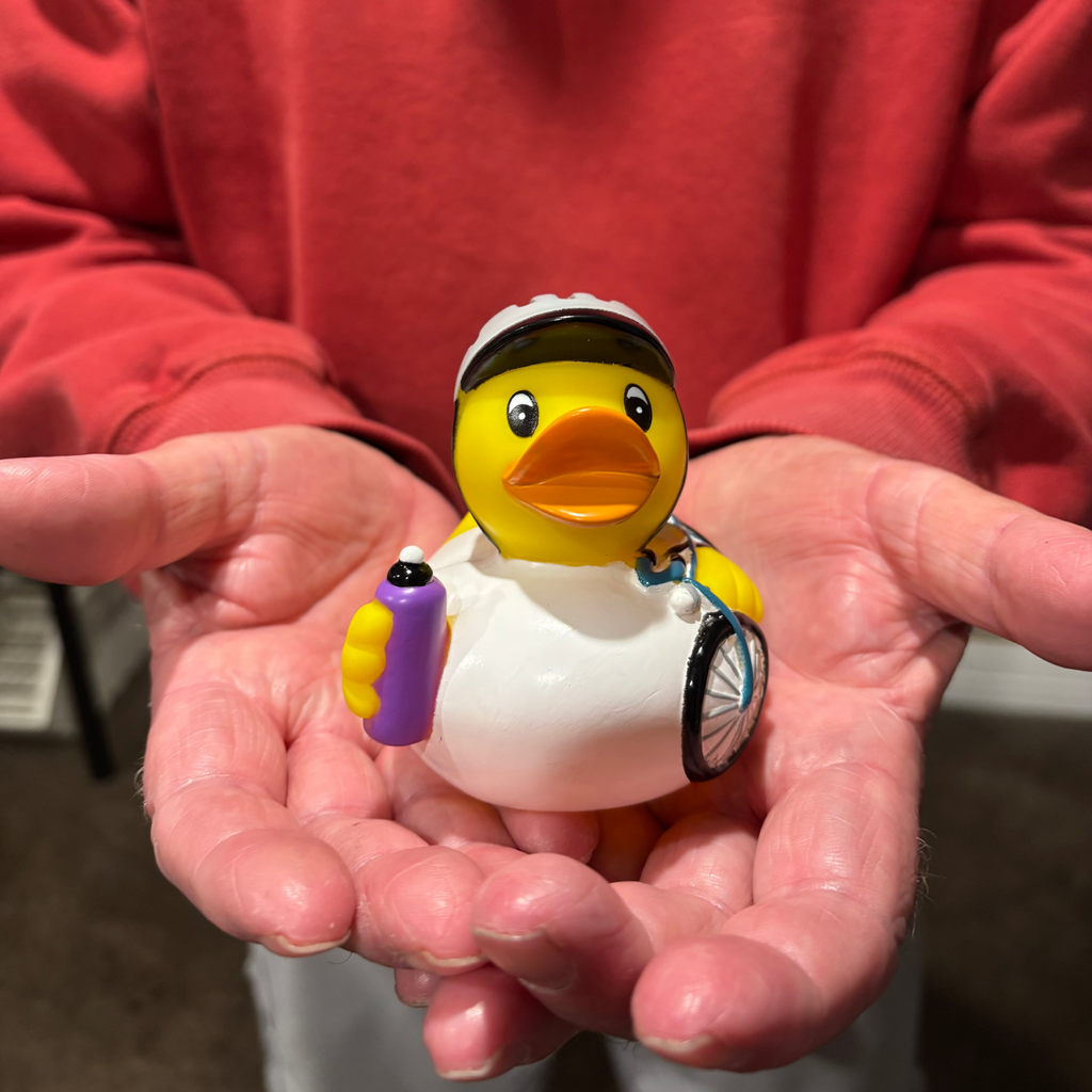 Person holding a rubber duck with a helmet and bicycle accessories